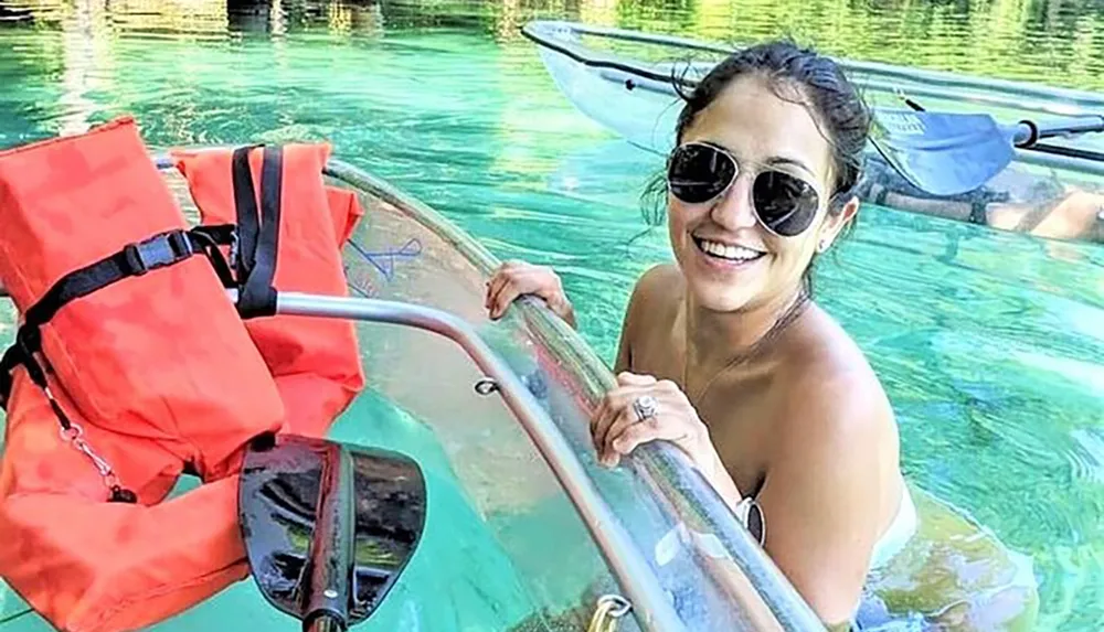 A smiling person is enjoying a kayak adventure on clear turquoise waters