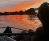 A person is kayaking on calm water during a vibrant sunset