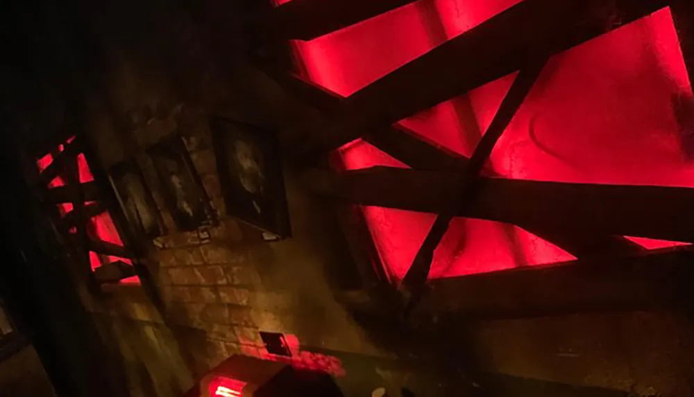 The image shows a dimly lit room with a red glow emanating from what appears to be an illuminated pentagram structure against a brick wall creating an ominous atmosphere