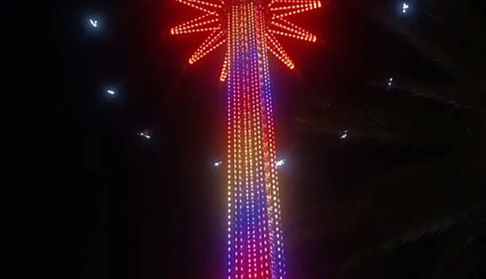 The image shows a vertical array of colorful lights radiating downwards from a central red star-shaped figure against a dark background possibly representing a festive decoration