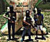 Two people wearing masks and protective vests are holding paintball guns standing next to an inflatable barrier in a paintball arena