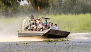 A group of people is enjoying an airboat tour through a scenic wetland area.