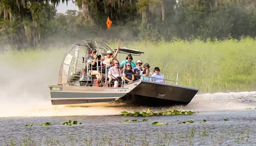 A group of people is enjoying an airboat tour through a scenic wetland area.