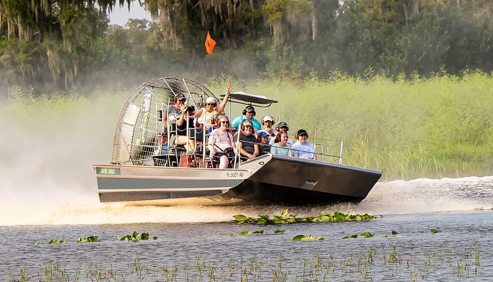 A group of people is enjoying an airboat tour through a scenic wetland area