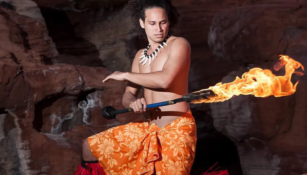A performer is skillfully handling a flaming torch against a rocky backdrop
