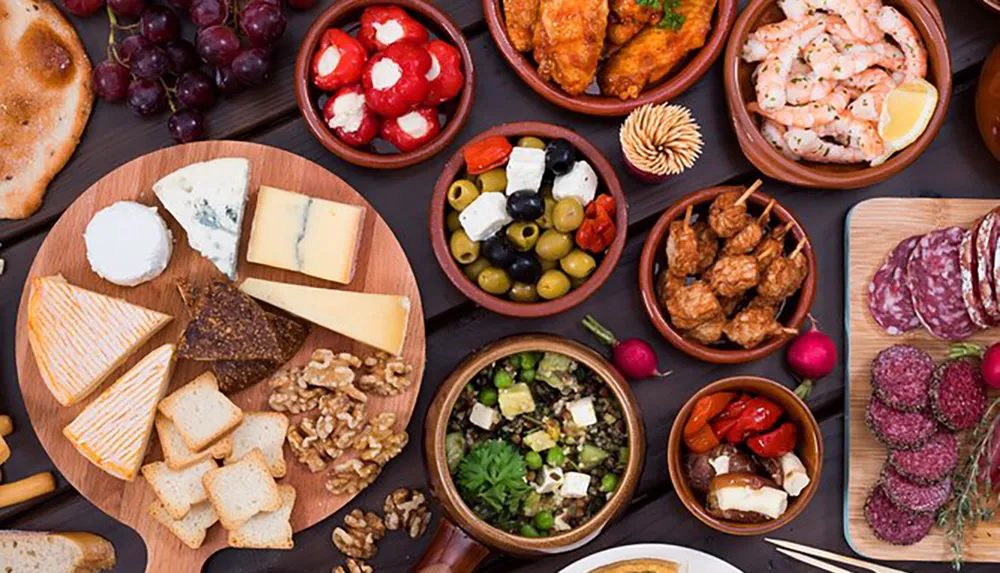 The image showcases a variety of Mediterranean or European appetizers featuring cheeses meats olives and other finger foods arranged for a group to share