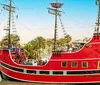 A red boat designed to look like a pirate ship named Pirates Ransom is docked in a marina with a clear sky in the background