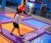 People of different ages are playing dodgeball on an indoor trampoline court with vibrant purple and blue colors