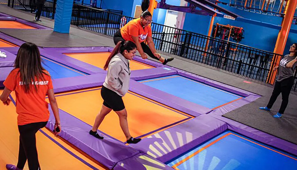 Individuals are engaging in activities on trampoline courts at an indoor recreation facility