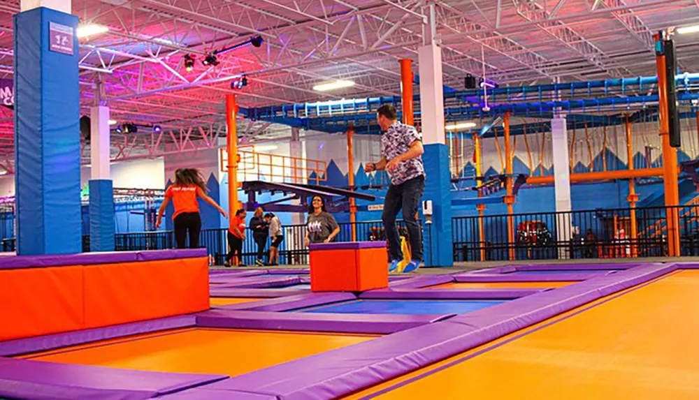 People are enjoying various activities in a colorful indoor trampoline park