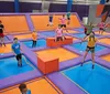 Children and adults are enjoying themselves while jumping on a colorful indoor trampoline park