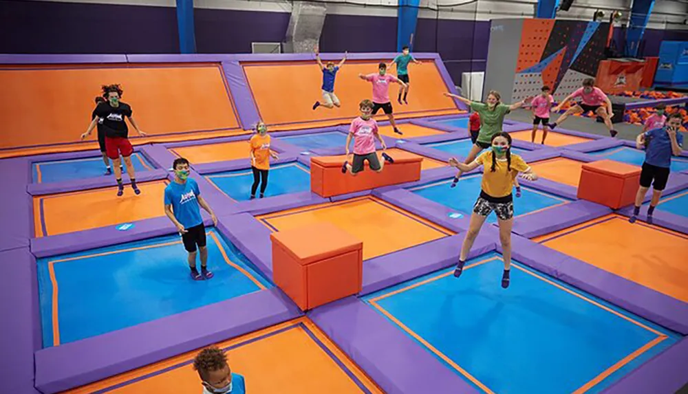 Children and adults are enjoying themselves while jumping on a colorful indoor trampoline park