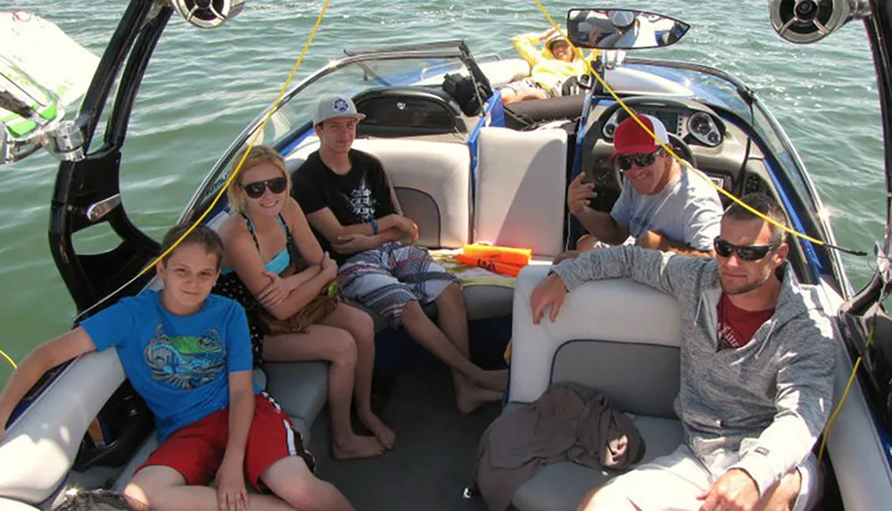 A group of people are enjoying a sunny day on a motorboat with the individuals smiling and posing for a casual photo