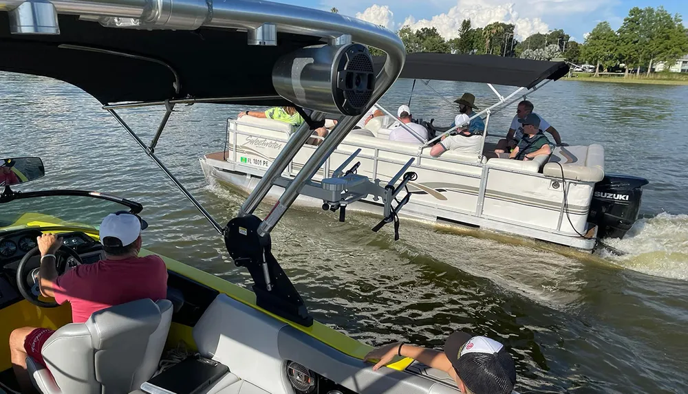 A person is piloting a motorboat while following another boat full of people on a sunny day