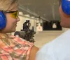 A woman is aiming a rifle at a shooting range under the supervision of an instructor