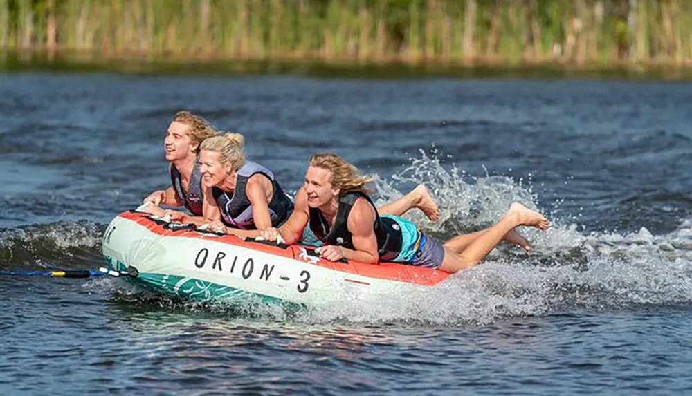 Four people are riding on a towable water tube with expressions of excitement and enjoyment