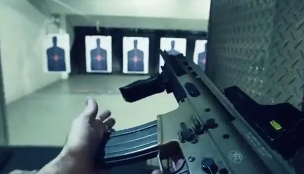 A person is loading a rifle likely at an indoor shooting range with paper targets in the background