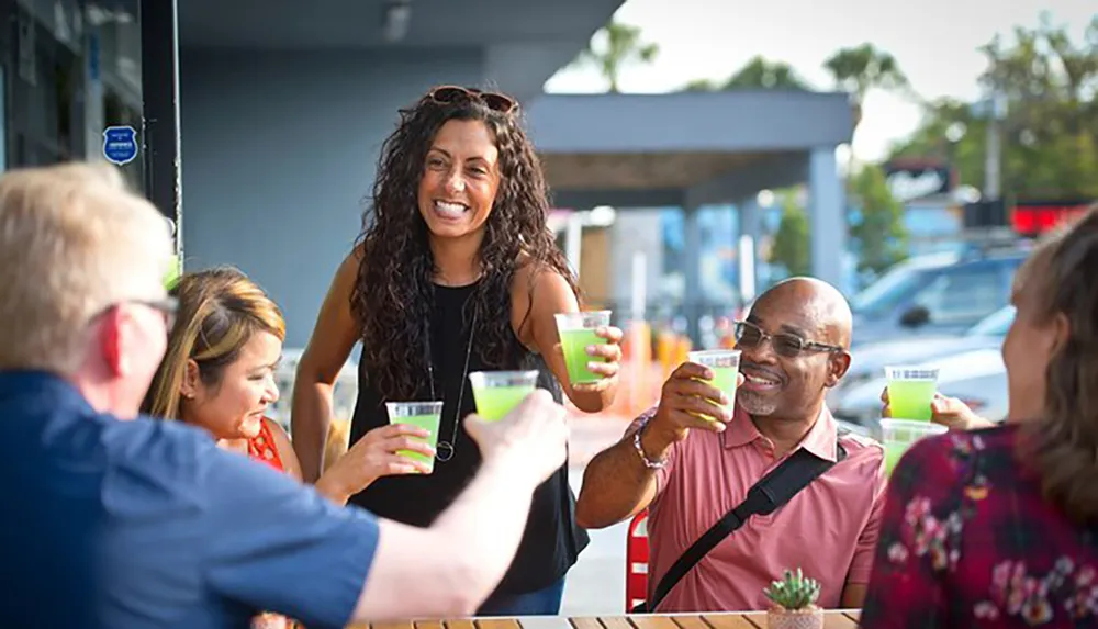 A group of people are enjoying drinks and smiling together at an outdoor table