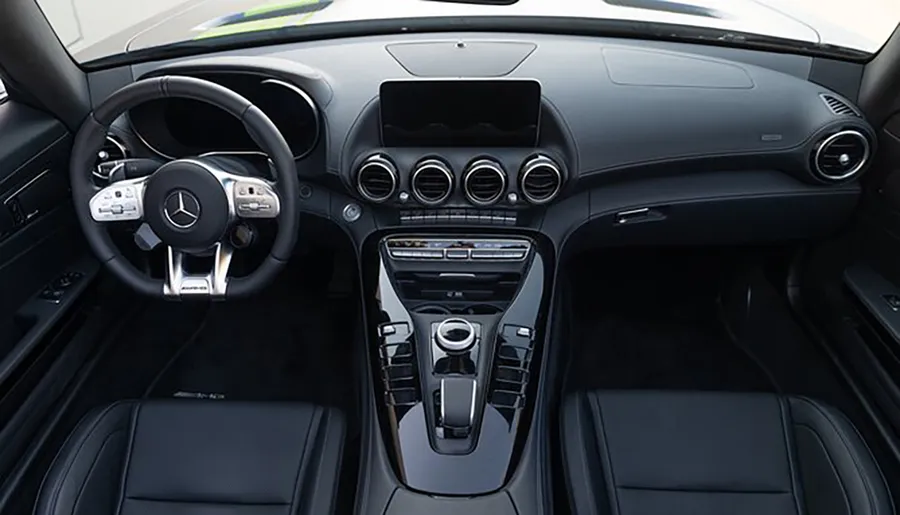 The image shows the modern and luxurious interior of a car with a focus on the steering wheel and center console.
