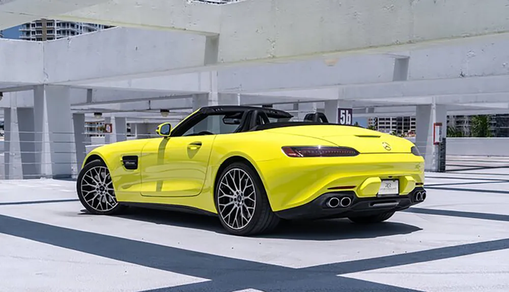 A bright yellow sports convertible is parked in a mostly empty concrete parking structure