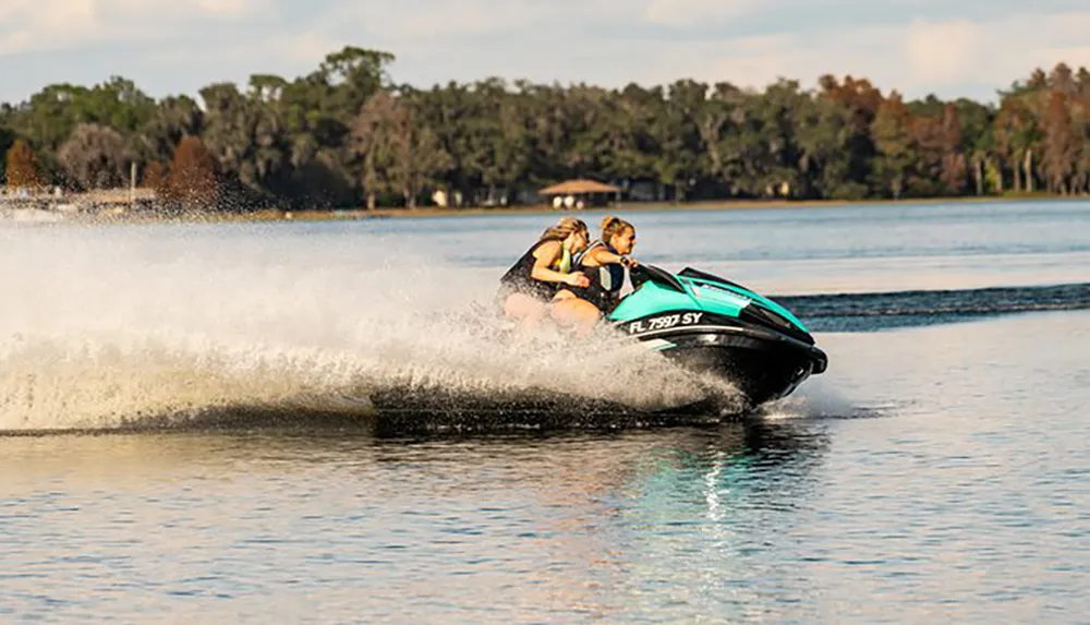 Two people are riding a jet ski at high speed on a body of water creating a large spray behind them