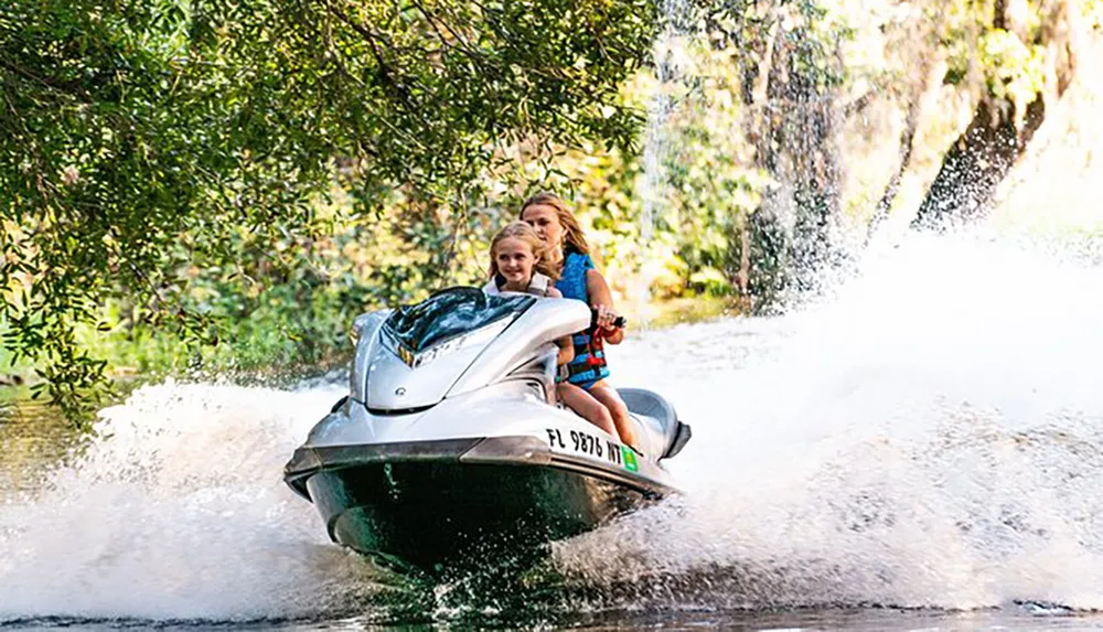 Two individuals are enjoying a ride on a jet ski creating a splash of water behind them