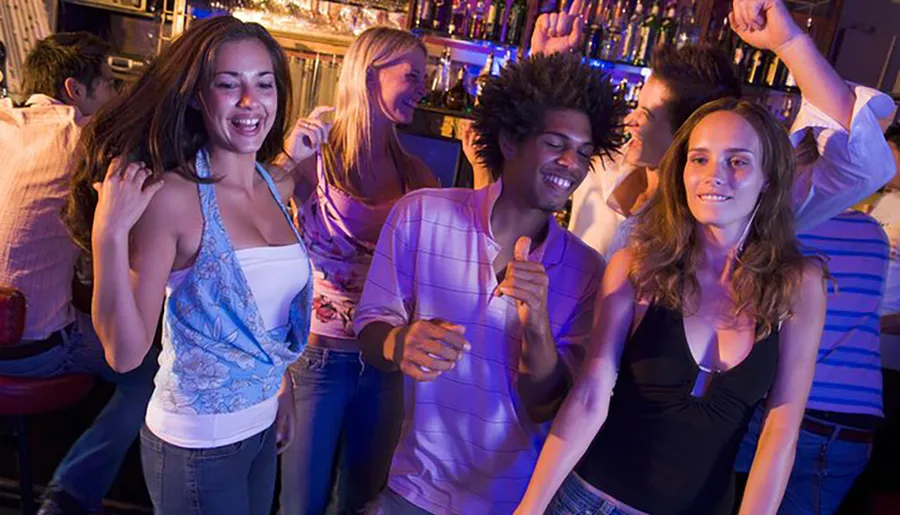 The image shows a group of joyful people dancing and having fun in a vibrant bar or club setting.