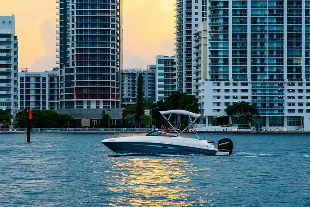 The image captures a motorboat cruising on the water near an urban skyline during sunset with the suns reflection on the water