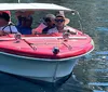 A group of people are enjoying a sunny day out on the water in a vintage red and white boat