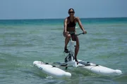 A person is riding a water bike on a calm sea, smiling at the camera.