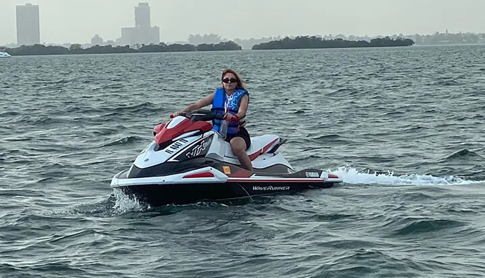 A person is riding a wave runner on a choppy water surface with a hazy skyline in the background