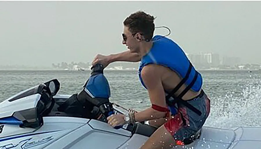 A person is riding a jet ski on the water, creating a spray as they speed along.