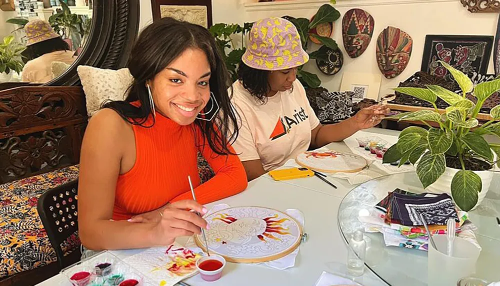 Two individuals are engaged in a painting activity smiling and concentrating on their work in a cozy art-filled room