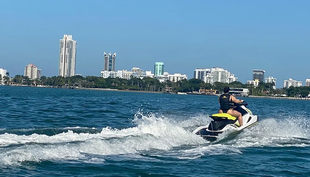 A person is riding a jet ski on the water with a city skyline in the background