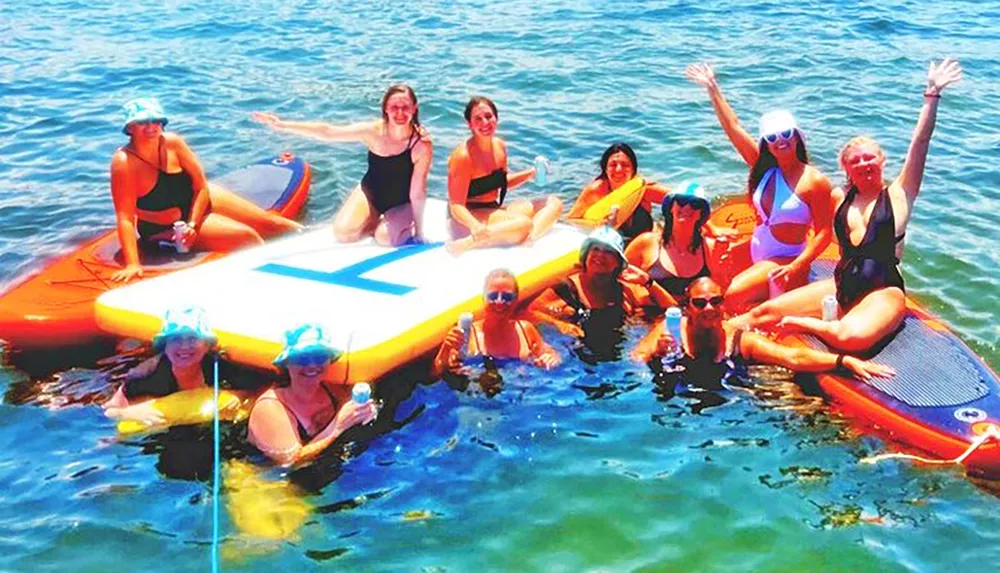 A group of people are cheerfully posing on stand-up paddle boards in the water