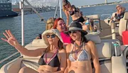 A group of people is enjoying a sunny boat ride with some individuals posing for the camera, showcasing a cheerful and leisurely experience.