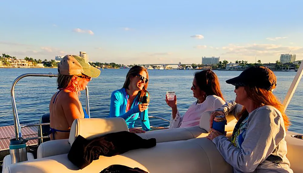 A group of friends is enjoying a boat ride and drinks on a sunny day with a scenic waterfront backdrop