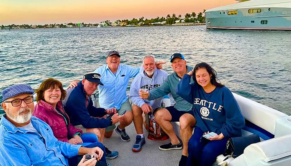 A group of adults is enjoying a boat ride together during sunset with smiles and casual poses