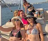 A group of cheerful people are enjoying a sunny day on a boat with drinks laughing and taking photos