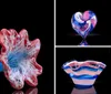 The image shows a beautifully crafted glass sculpture with vibrant blue and red colors resembling a sea creature or flower reflected on a dark surface
