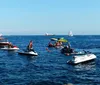 Two people are riding a jet ski across choppy water creating a spray behind them