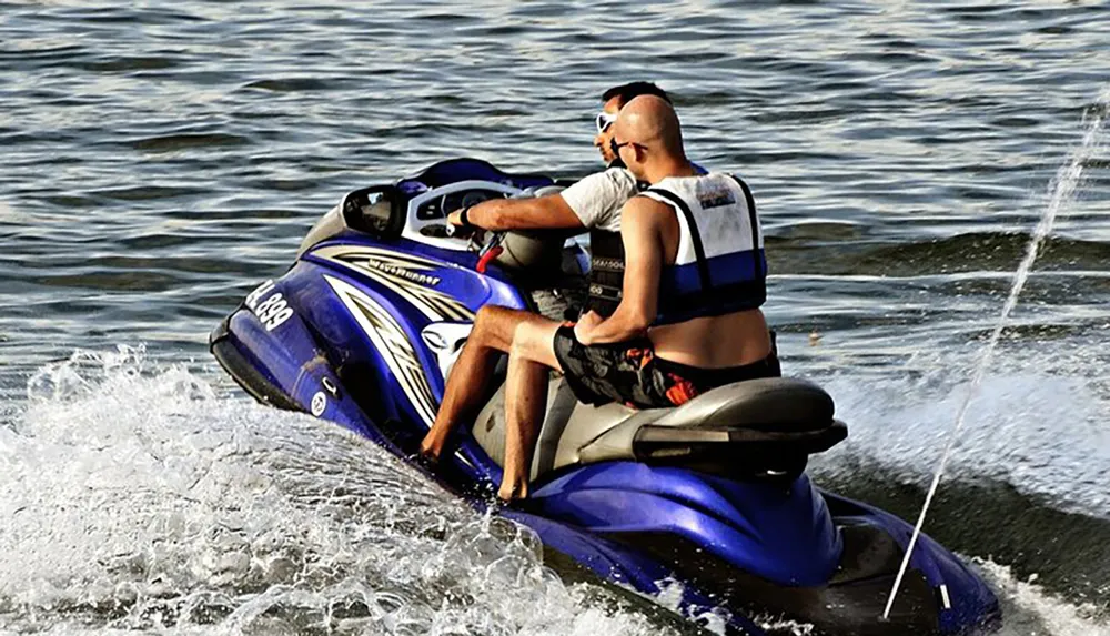 A person is riding a blue and white jet ski on the water creating a splash