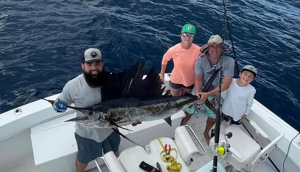 Four people are posing with their catch a large fish on a boat expressing pride and happiness in their successful fishing adventure