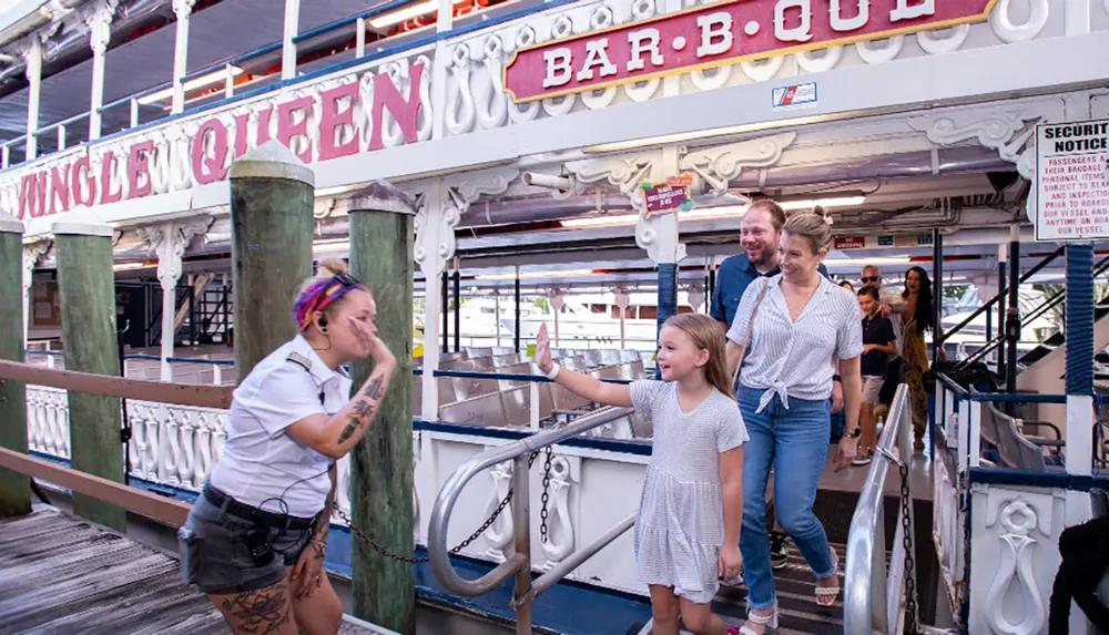 A happy family is being greeted by a smiling crew member as they board the Jungle Queen Bar-B-Que riverboat for a cruise