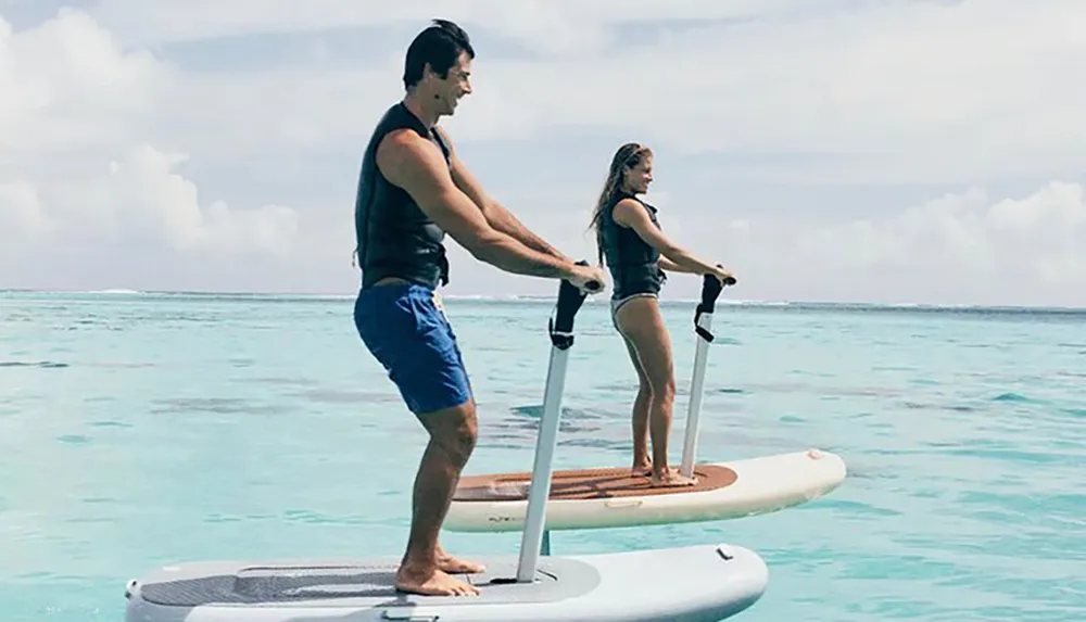 A man and a woman paddleboarding on a calm clear ocean