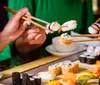 A person is preparing sushi by rolling ingredients in seaweed on a bamboo mat