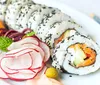 A person is preparing sushi by rolling ingredients in seaweed on a bamboo mat