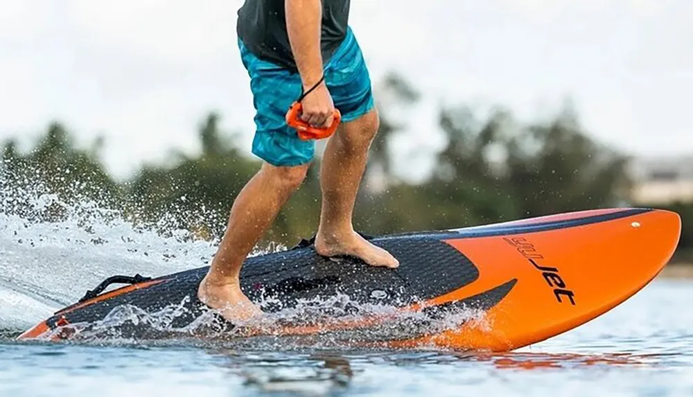 A person is stand-up paddleboarding skimming across the water surface with a focus on their lower body and the board