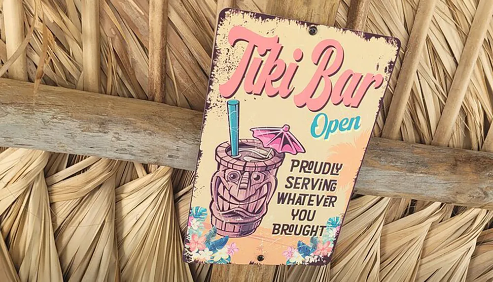 This image shows a whimsically designed Tiki Bar Open sign hanging on a thatched background humorously indicating that the bar is proudly serving whatever you brought