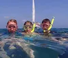 Two people wearing snorkeling gear are jumping off a sailboat into the sea while others watch